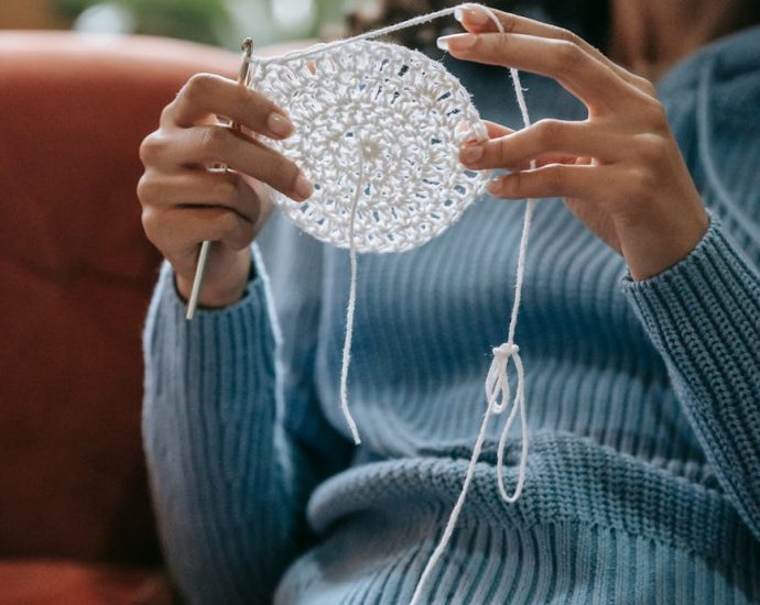 a woman in blue knitted sweater holding a white yarn