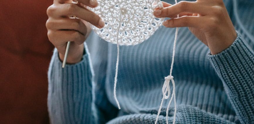 a woman in blue knitted sweater holding a white yarn