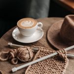 coffee drink beside a knitted material on wooden table