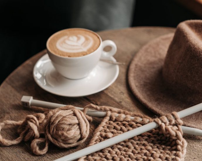 coffee drink beside a knitted material on wooden table